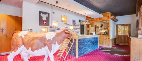 Une pièce comprenant une grande sculpture de vache, un comptoir d’accueil et un tapis rouge à motifs.