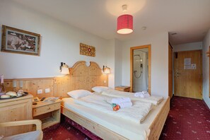 Habitación de hotel con cama de madera, mesitas de noche, un espejo, armario de madera y alfombra roja.