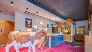 Una habitación con una estatua de vaca, una barra de madera y un suelo con estampado rojo.