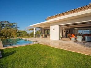 A modern house with a swimming pool, outdoor seating, and a large glass door leading to the interior. - Sea View • Pool • Near Saint-Tropez (Sainte Maxime)