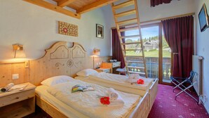 Een kamer met twee bedden, een houten plafond, een raam met uitzicht, een ladder en een stoel.