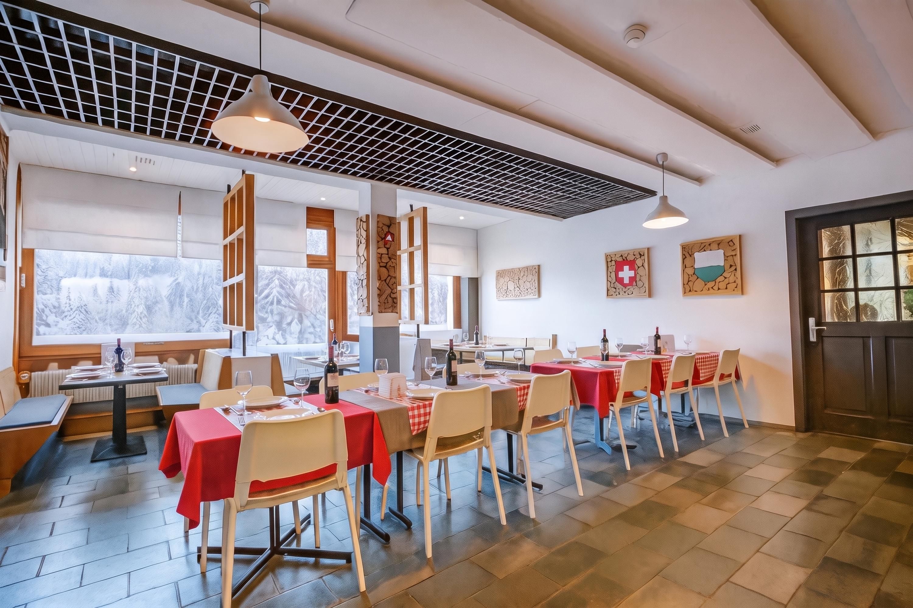 A restaurant with multiple tables, chairs, and a view of snowy mountains through large windows.