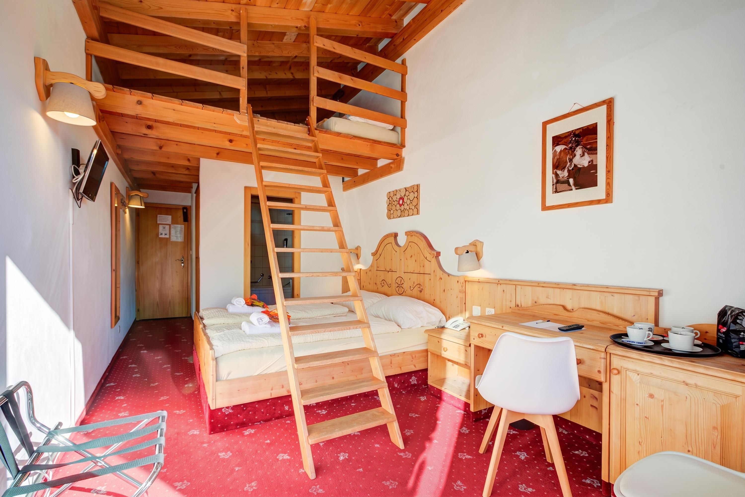 A room with a loft bed, a desk, a chair, and a ladder.