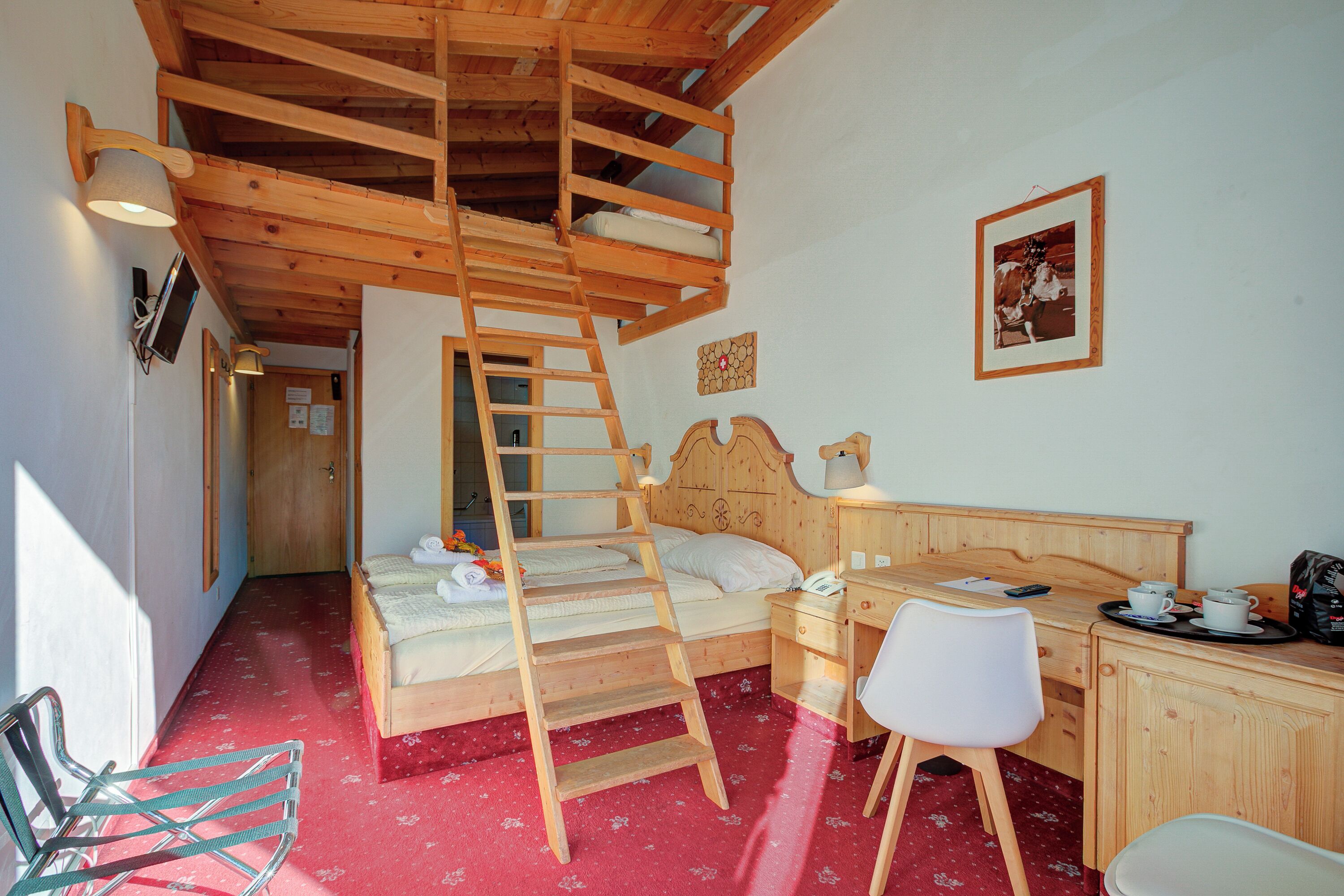 Un dormitorio con una escalera de madera, una cama, un escritorio, una silla y una mesita con tazas y una bolsa.