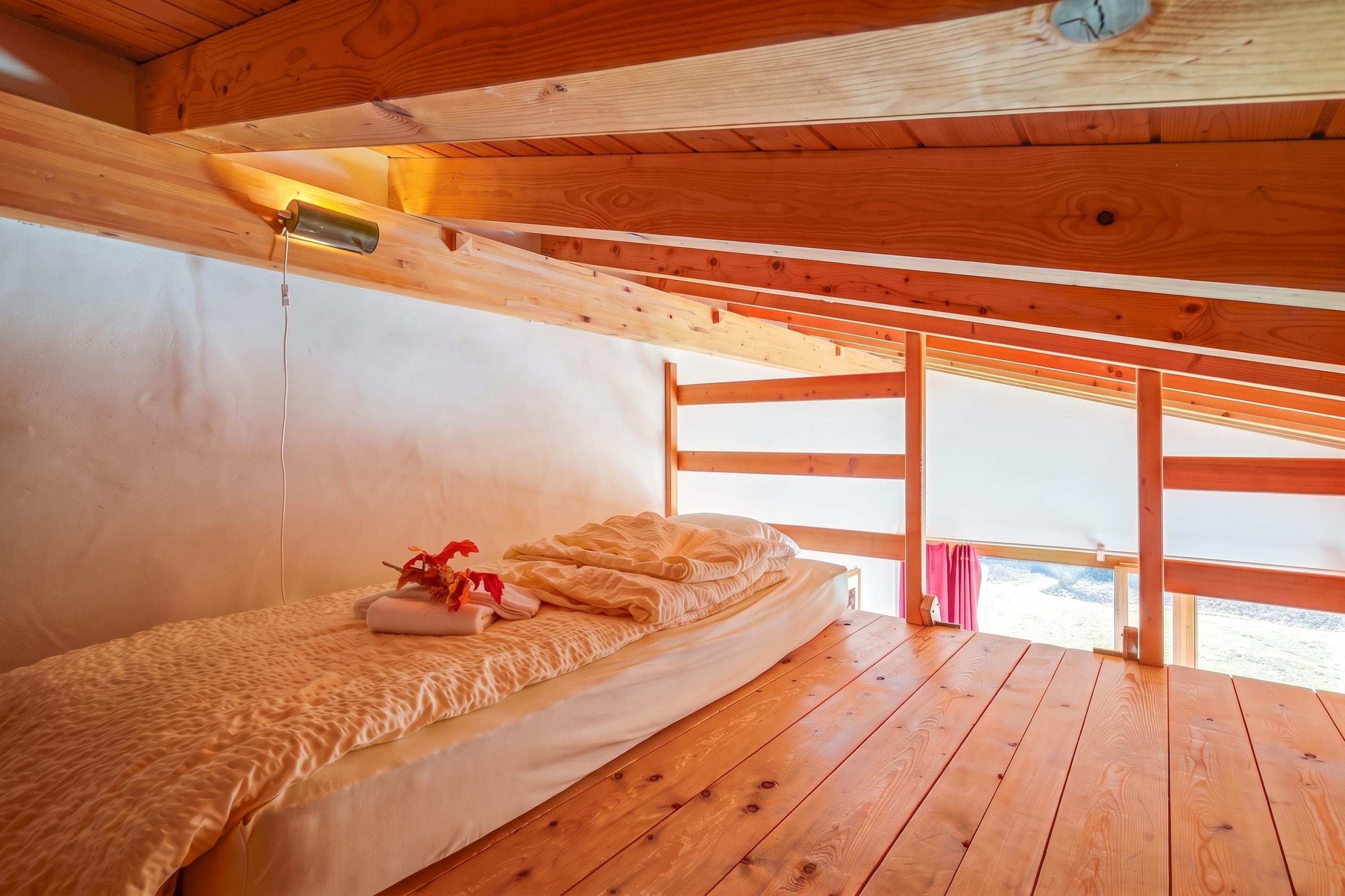 Ein Zimmer in einer Holzhütte mit Etagenbett, Nachttischlampe und Fenster mit Blick.