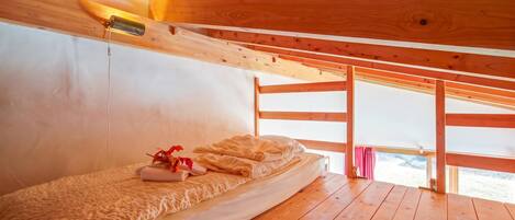 Ein Zimmer in einer Holzhütte mit Etagenbett, Nachttischlampe und Fenster mit Blick.