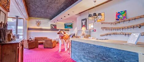Un vestíbulo de hotel con alfombra roja, muebles de madera, un mostrador de recepción y decoración en las paredes.