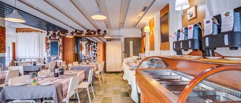 A restaurant with multiple dining tables, a buffet area, and a wall-mounted coffee station.