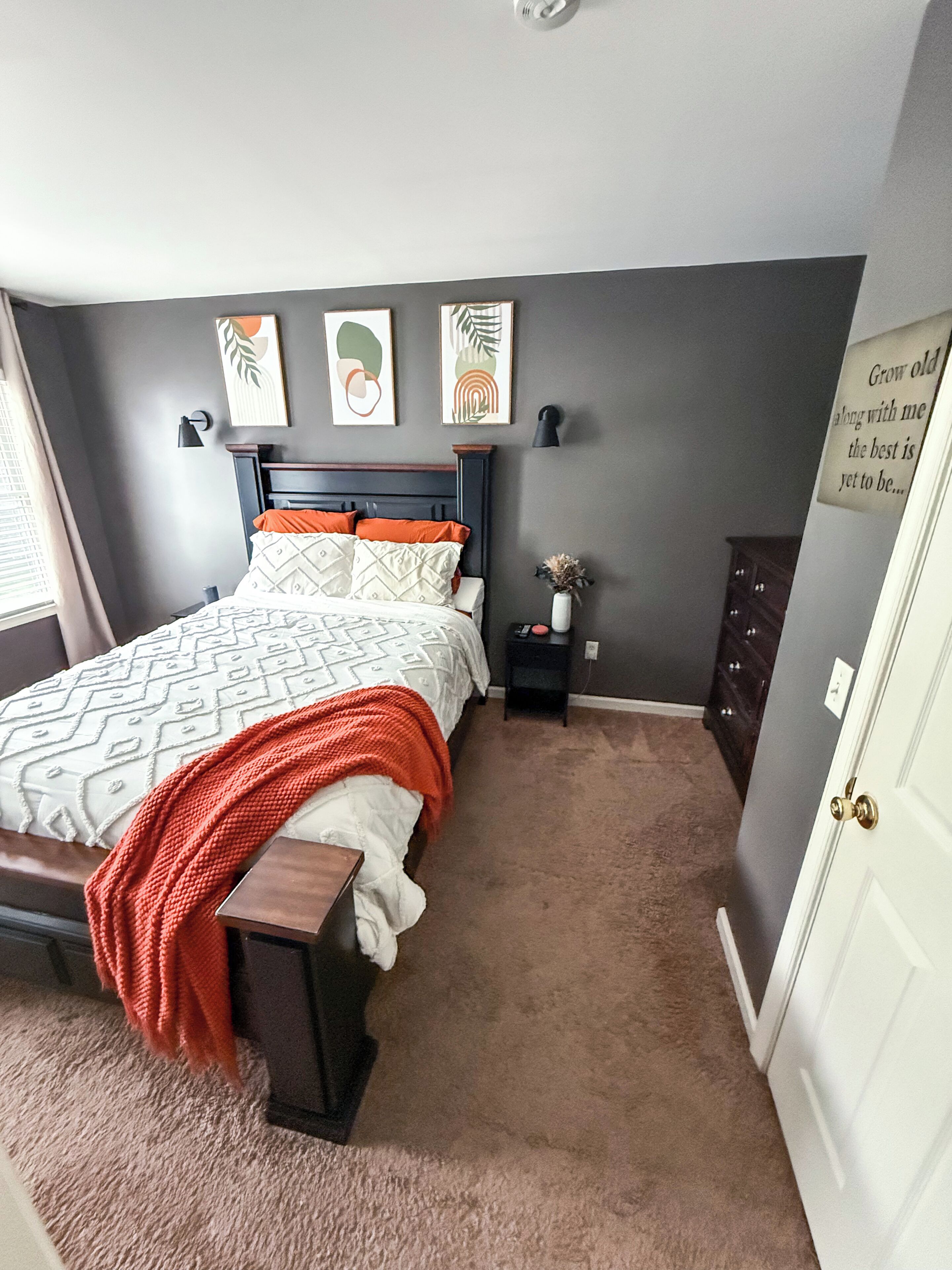 Une chambre à coucher avec un lit, une table de chevet, une commode et une porte.