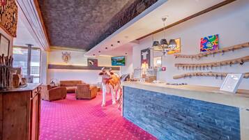 Eine Hotelhalle mit rotem Teppich, Holzmöbeln, einem Empfangsbereich und Wanddekorationen.