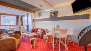 Una sala de estar acogedora con sofás, una mesa de centro, televisión y chimenea.
