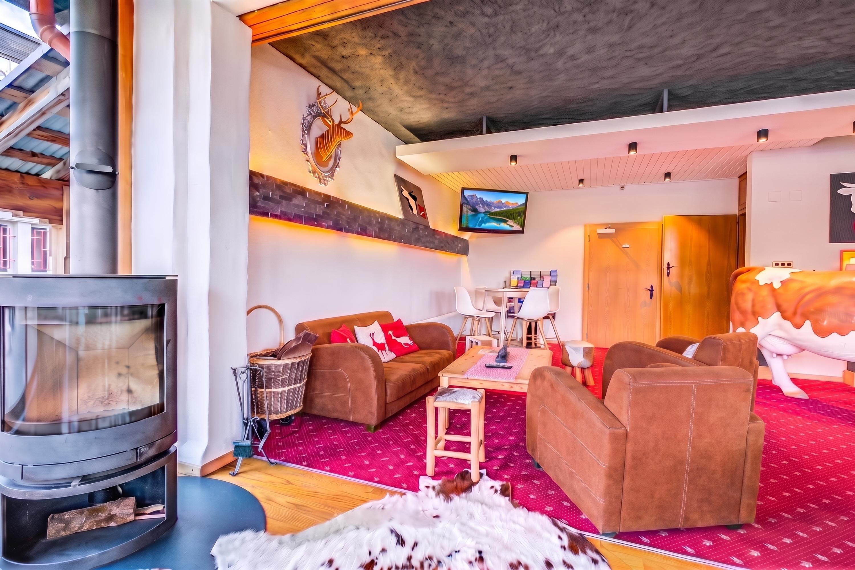 Ein gemütliches Wohnzimmer mit Kamin, bequemen Sitzmöglichkeiten, einem Fernseher und einer Wanddekoration.