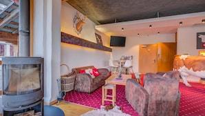 Un salon chaleureux avec une cheminée, des fauteuils confortables, un téléviseur et une tête de cerf décorative accrochée au mur.
