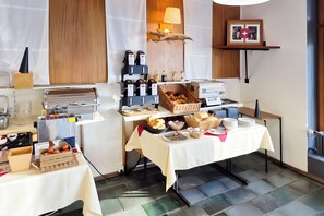 Montaje de un bufé de desayuno con diversas opciones de comida y una estación de café.