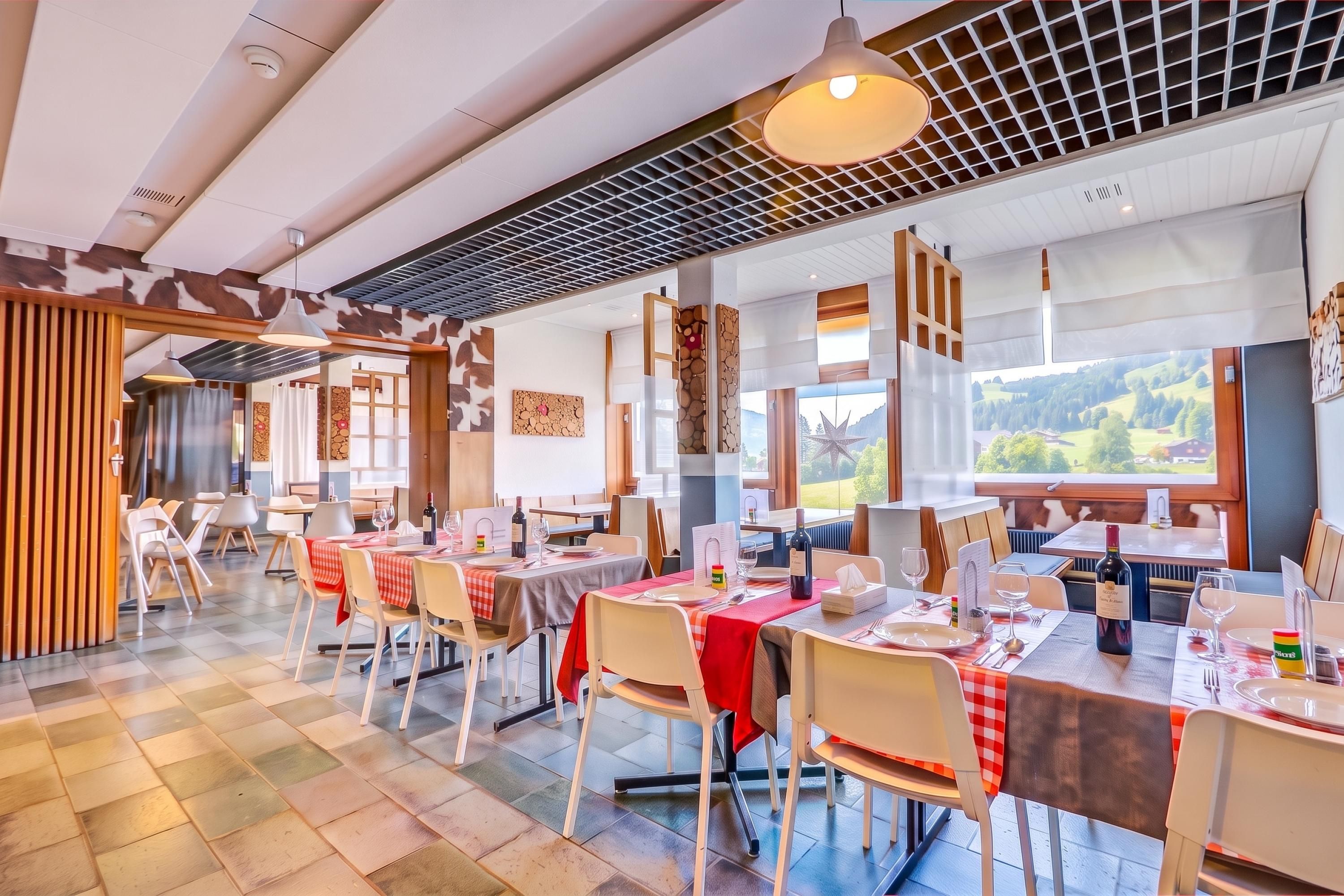 Ein Restaurant mit mehreren Tischen, Stühlen und Blick ins Freie.