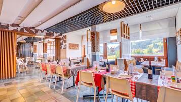 Un restaurant doté de nombreuses tables, de chaises et offrant une vue sur l’extérieur.