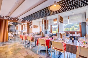 Un restaurante con varias mesas, sillas y vistas al exterior.