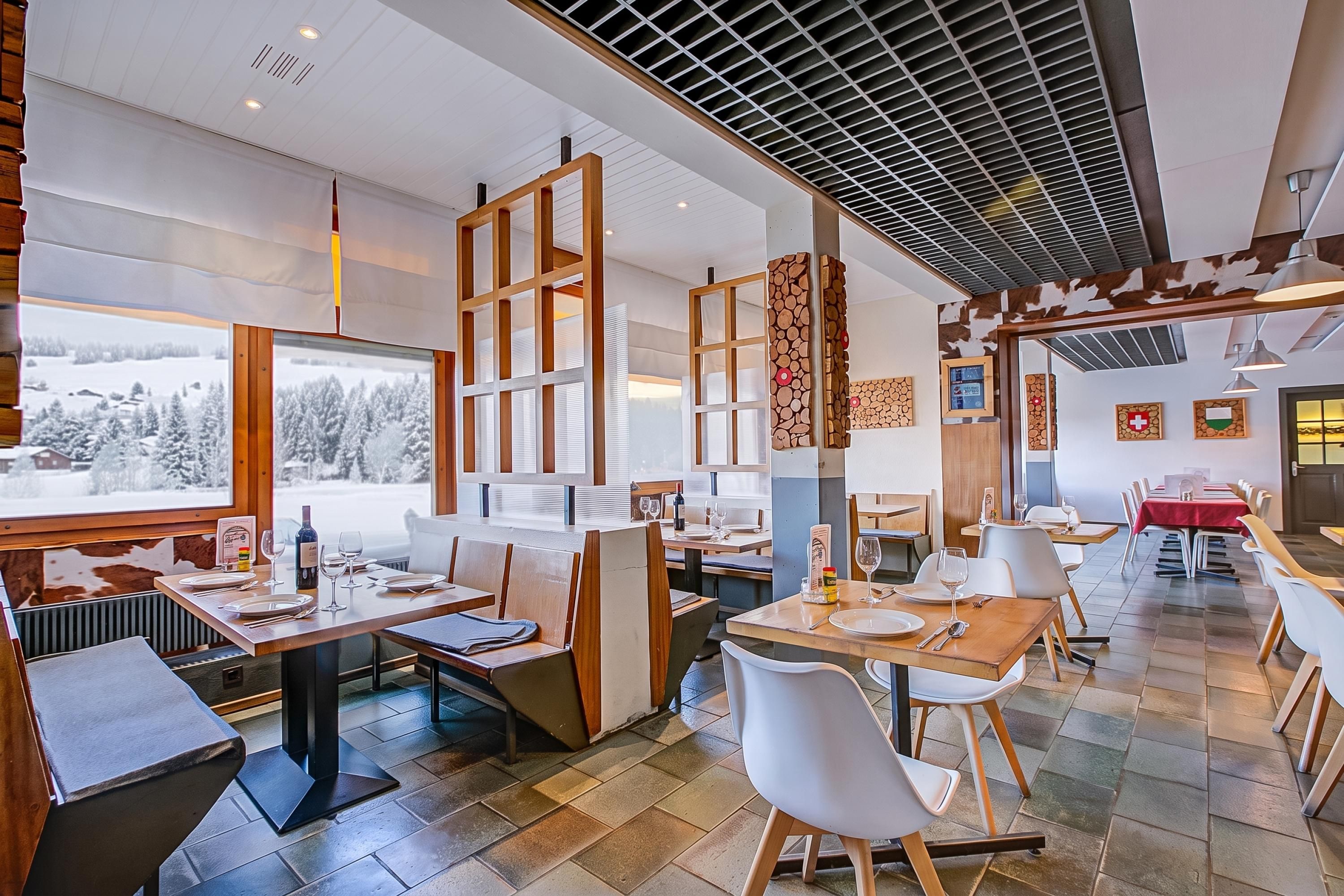 Un restaurant au décor moderne, avec des meubles en bois et une vue sur des montagnes enneigées.