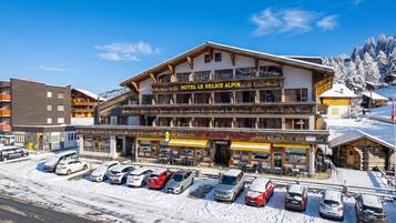 Ein Hotel im traditionellen alpinen Stil mit einem markanten Balkon und einem Schild mit der Aufschrift 'HOTEL LE RELAIS ALPIN'.