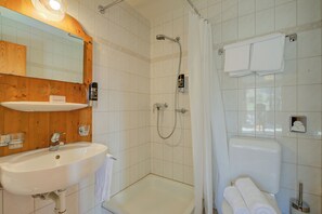 Un baño con lavabo, espejo, ducha e inodoro.