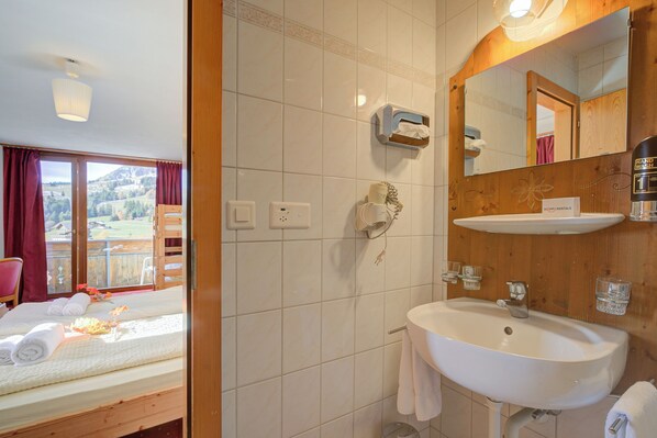 Habitación de hotel con cama, baño con lavamanos y espejo, y vista al exterior.