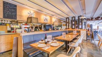 Ein Restaurantinnenraum mit Holztischen und -bänken, einer Bar und einer Tafel mit der Speisekarte.