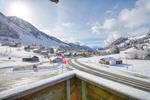 Un pueblo cubierto de nieve en la montaña, con casas de madera y un camino sinuoso.
