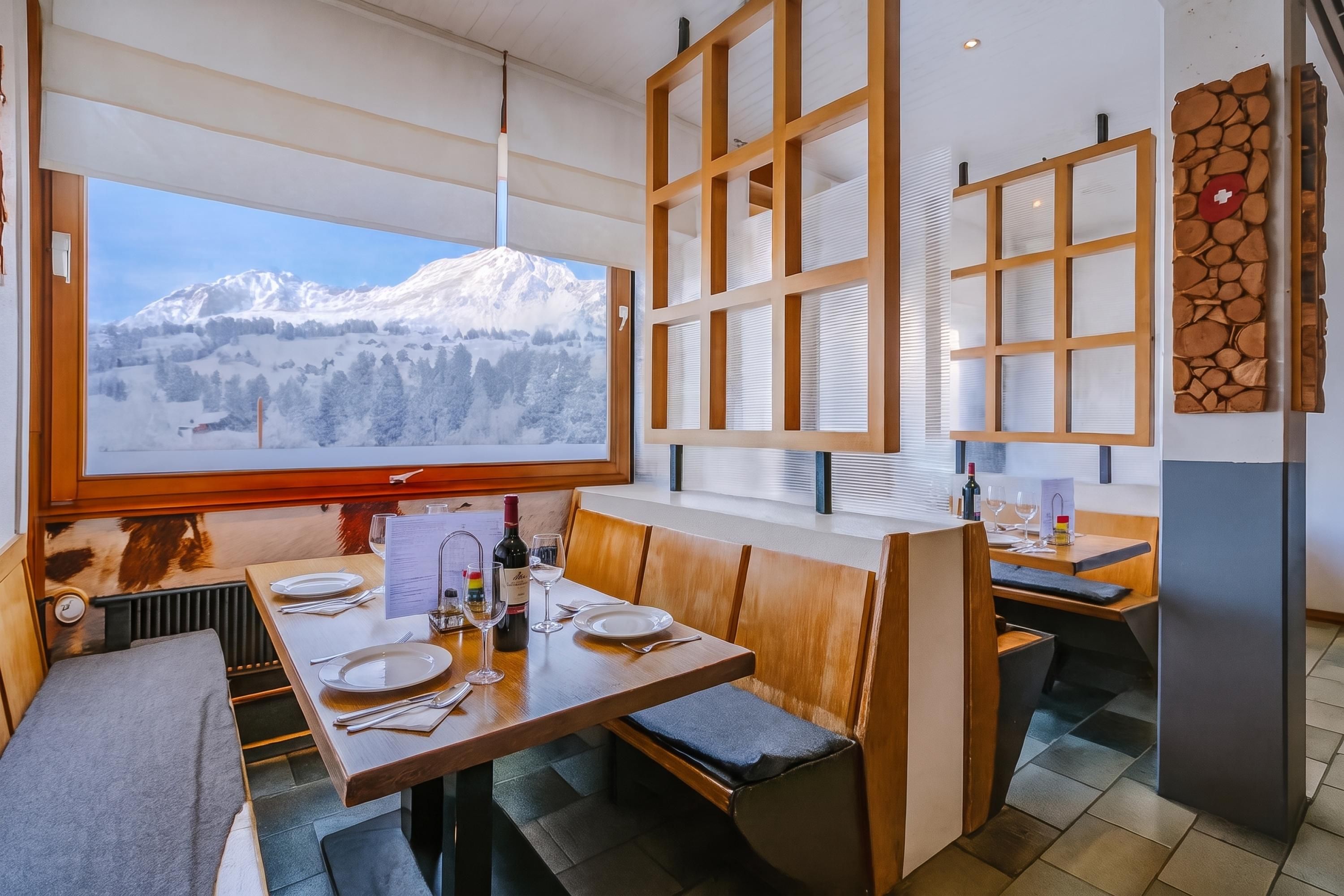 A restaurant with a mountain view, wooden furniture, and a menu stand.