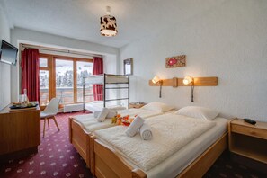 Habitación de hotel con cama, escritorio, silla y vista a un paisaje nevado.