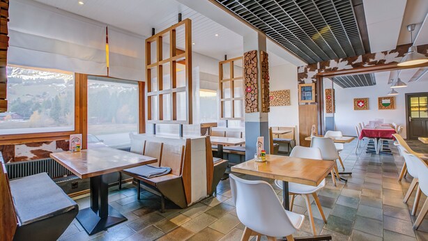 Un restaurant doté de tables hautes et de banquettes, de grandes fenêtres offrant une vue dégagée et d’un design moderne au niveau du plafond.