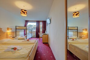 Une chambre d’hôtel avec deux lits, un bureau, une chaise, une télévision et une fenêtre avec des rideaux.