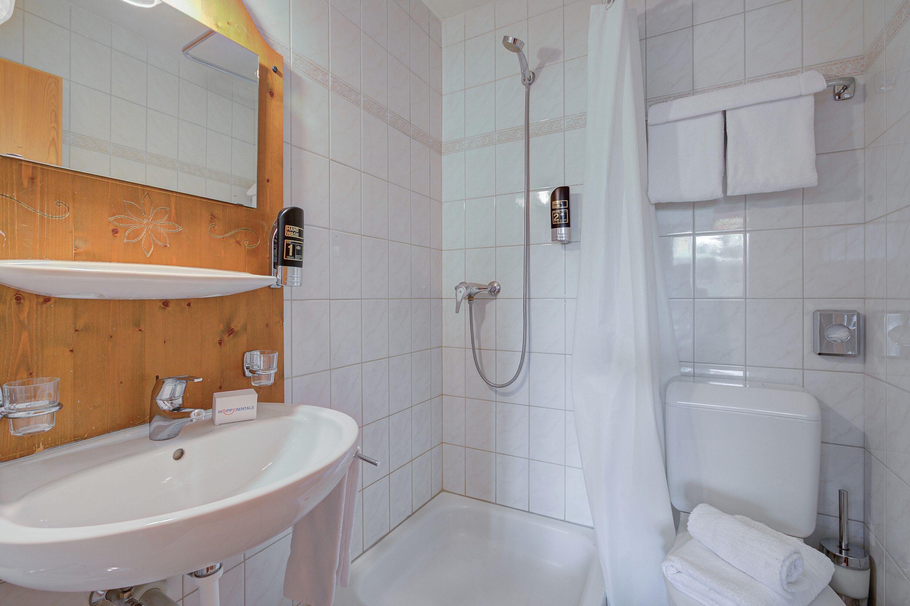 Ein Badezimmer mit Waschbecken, Spiegel, Dusche und Toilette.