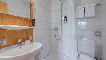 Ein Badezimmer mit Waschbecken, Spiegel, Dusche und Toilette.
