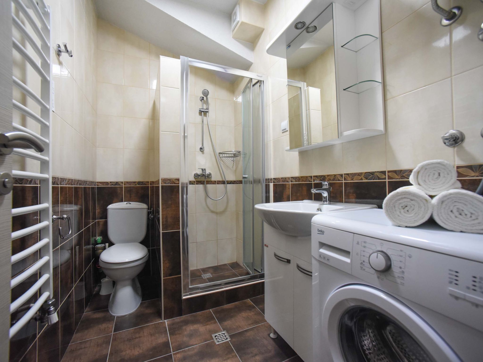 A bathroom with a toilet, shower, and washing machine.