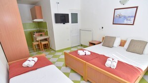 Ett hotellrum med två sängar, ett litet pentry, en TV och en tavla på väggen.