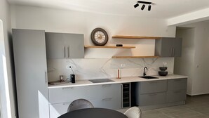 A modern kitchen with grey cabinets, a marble countertop, and a round dining table with chairs. - Appartement mit Pool by Interhome (Herceg Novi)