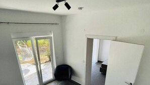 Ein Zimmer mit einem Bett, einem Deckenventilator und einer Schiebetür zu einem Außenbereich mit einer Hängematte.
