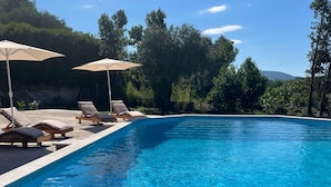 A clear blue swimming pool with lounge chairs and umbrellas, surrounded by greenery and trees. - Appartement mit Pool by Interhome (Herceg Novi)