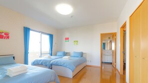 Habitación de hotel con dos camas, baño y zona de cocina.