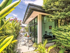 A modern house with a glass exterior, a patio with outdoor furniture, and lush greenery. - "Villa Sabai" mit Terrasse by Interhome (Pattaya)