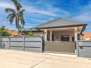 A house with a tiled roof, a gated entrance, and a stone wall. - "Villa Sabai" mit Terrasse by Interhome (Pattaya)