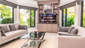 Un soggiorno moderno con due divani, un tavolino da caffè e un mobile TV con schermo che mostra diversi canali.