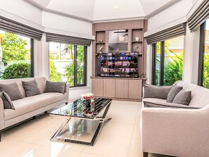 A modern living room with two sofas, a coffee table, and a TV stand with a screen displaying various channels. - "Villa Sabai" mit Terrasse by Interhome (Pattaya)