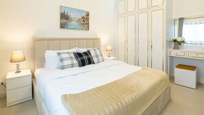 A bedroom with a bed, nightstands, a dresser, a mirror, and a painting on the wall.