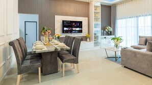 A modern living room with a dining area, a chandelier, and a TV mounted on the wall.