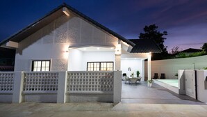 A modern house with a covered patio, a fenced yard, and a swimming pool.