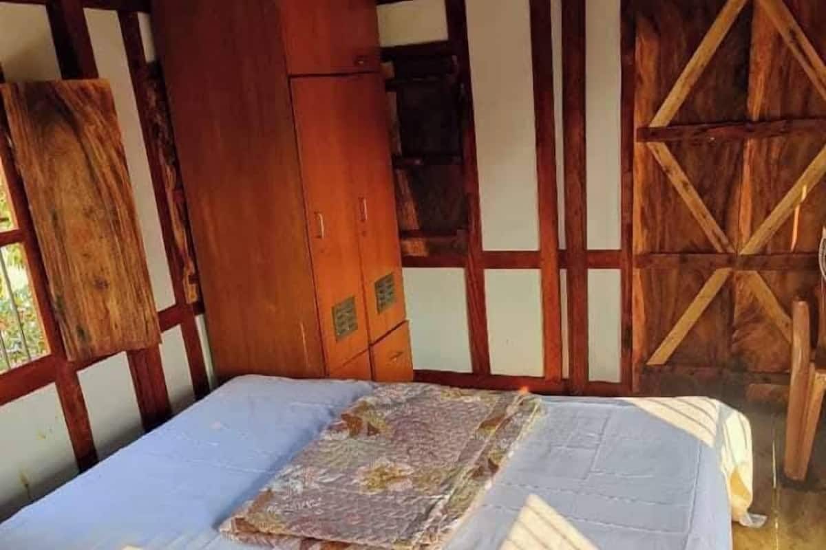A room with a bed, wooden wardrobe, and a wooden wall panel.