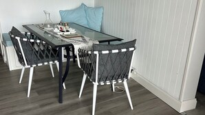 A dining area with a glass table, black and white chairs, a woven rug, and a blue pillow on a white wall. - Waterfront 3 bed Townhouse in gated community (Patterson Lakes)