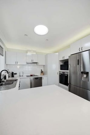A modern kitchen with white cabinets, stainless steel appliances, and a central island.