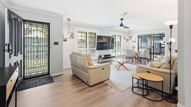 A modern living room with a sofa, TV, and dining area. - Belle Escapes - Fulton Retreat (Holdfast Bay)